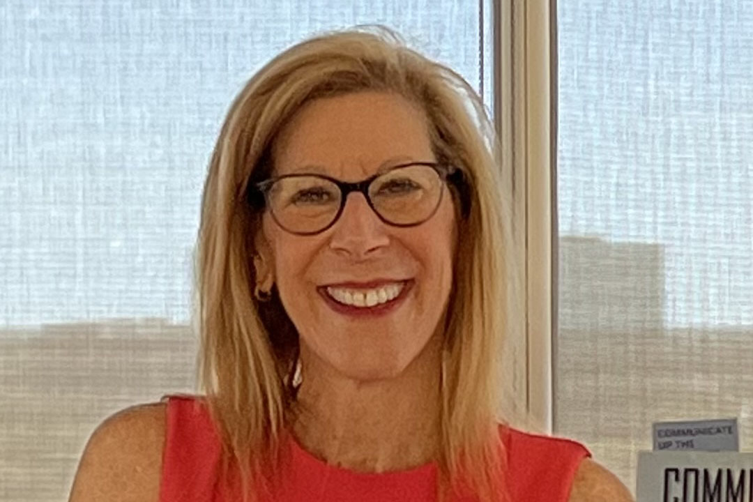 Woman with shoulder length hair and a red shirt smiling broadly